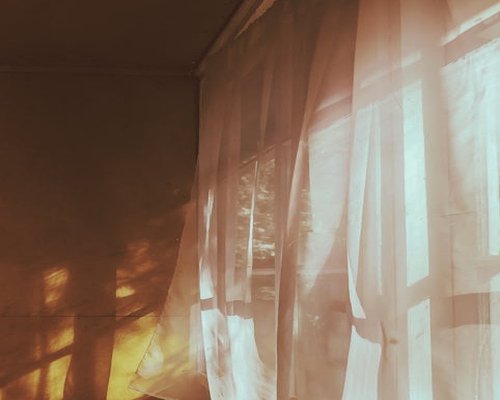 Soft morning sunshine filling a minimal living room apartment in Puebla with curtains diffusing light