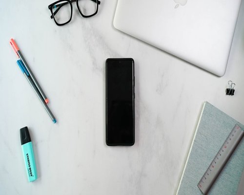 A clean workspace desktop organizing tools and a notebook next to a smartphone